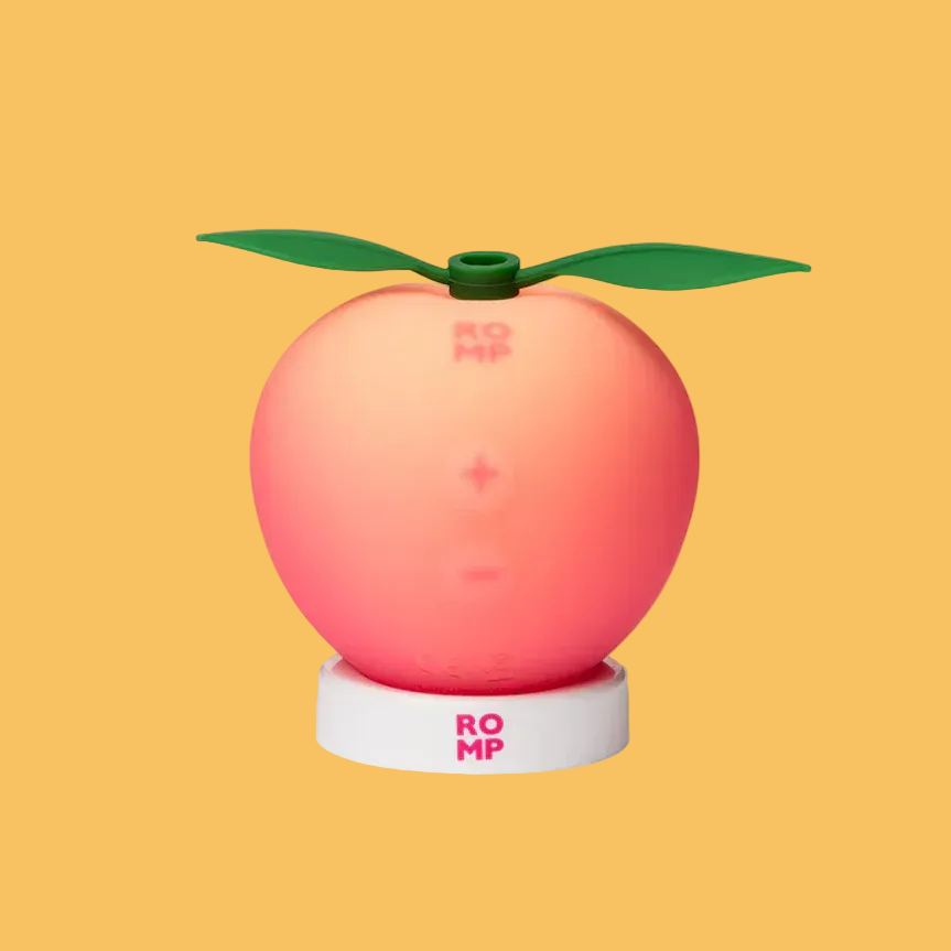 A yellow, oval-shaped electronic device with a power button sits among whole and sliced lemons on a colorful, vibrant background.