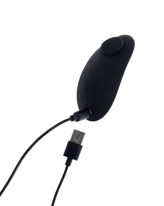 A black wireless Sportsheets mouse being charged with a USB cable against a white background.