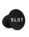 A pair of black circular Blush Slut Silicone Butt Plugs made of platinum cured silicone, with the word "slut" printed in white capital letters, against a white background.