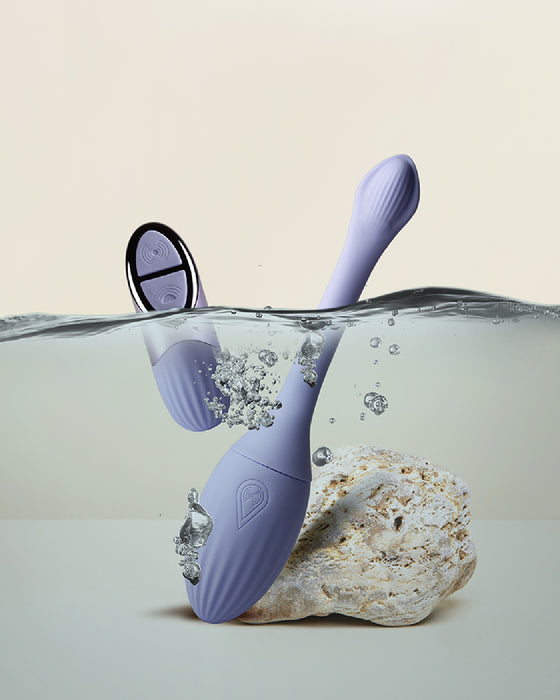 A Niya N1 Vibrating Egg & Kegel Exerciser with Remote from Rocks Off making a splash as it balances on a rock, partially submerged in clear water, illustrating its water-resistant capabilities.