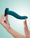 A person holding a Fun Factory Limba Flex Medium Silicone Dildo in Deep Sea Blue against a light blue background. The dildo, designed with a smooth finish and an ergonomic shape, features a suction base.