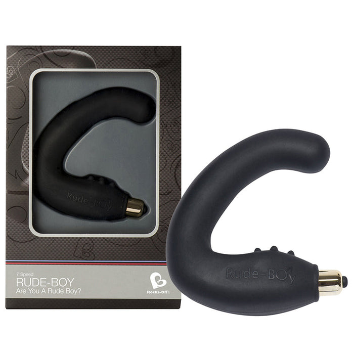 A black, curved silicone Rude-Boy Dual Prostate & Perineum Stimulator is shown beside its box, which features a clear window displaying the product along with branding and information.