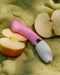 A pink LELO Gigi 2 Silicone G-Spot Vibrator lies next to sliced apples on a textured green surface.