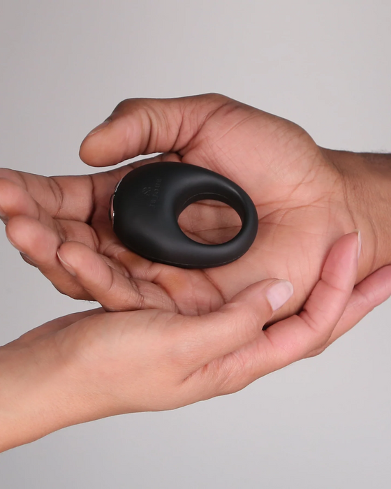 Two hands holding a Je Joue Mio Vibrating Cock Ring - Black against a neutral background.