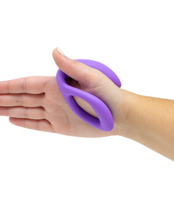 Hand with a We-Vibe Sync O Hands-Free Wearable Couples Vibrator - Purple silicone grip strengthener device wrapped around the fingers for exercise.