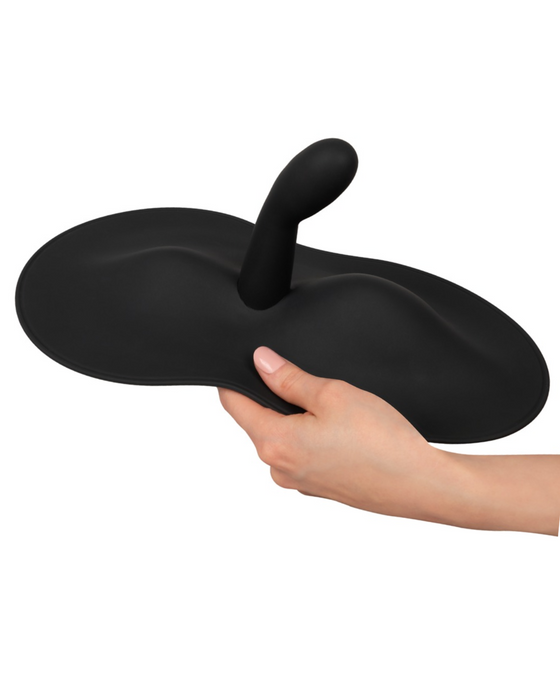 A person holding a black, cartoonish, anvil-shaped object with a central handle, resembling the Orion VibePad 3 Ride On Hands-Free Humping Vibrator with G-Spot Probe from a classic animated film.