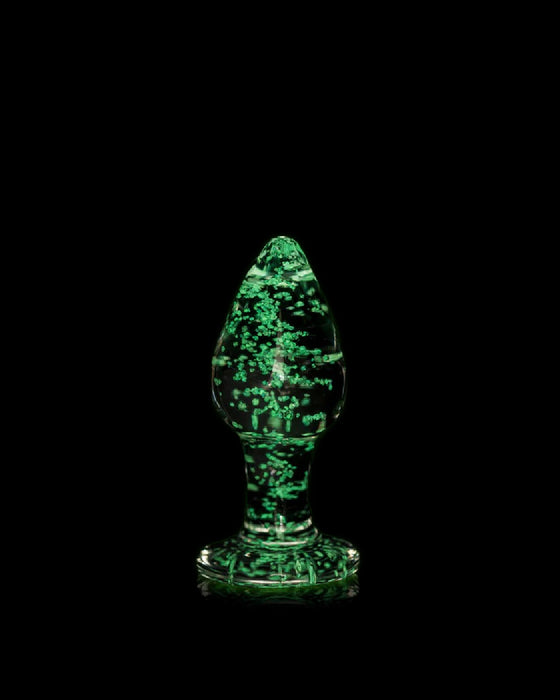A translucent green borosilicate glass sculpture with a swirling pattern, shaped like a tree or flame, set against a black background.