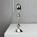 The Aneros Tempo Stainless Steel Anal Stimulator stands upright on a white surface against a plain gray background, showcasing its metallic, reflective finish and ergonomic design—ideal for temperature play.