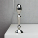 The Aneros Tempo Stainless Steel Anal Stimulator stands upright on a white surface against a plain gray background, showcasing its metallic, reflective finish and ergonomic design—ideal for temperature play.