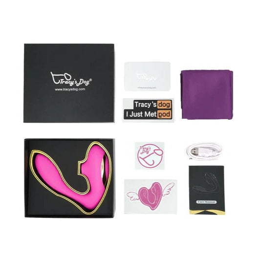 Unboxed Tracy's Dog OG Clitoral Sucking G-Spot Vibrator set with pink toy, black and pink box, USB cable, manual, purple pouch, and assorted stickers and cards laid out neatly on a white background.