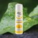 A white bottle of Pjur Med Soft Glide Silicone Lubricant with Jojoba Oil stands upright on a water-dappled green leaf. Designed for sensitive intimate areas, the bottle has yellow, gray, and white labeling.