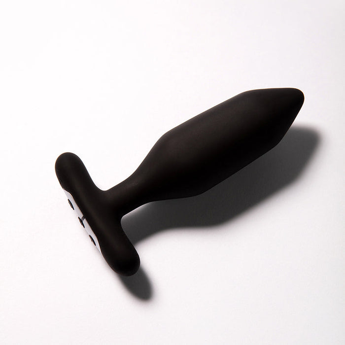 The Je Joue Onyx Large Powerful Remote Control Vibrating Butt Plug features a black silicone, tapered shape with a flared base, shown on a white surface with shadow, and delivers deep rumbly vibrations for enhanced pleasure.