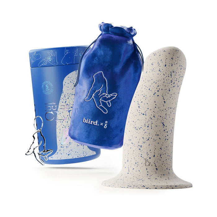 The Boo Thick 5.5 Inch Silicone Suction Cup Dildo, featuring a speckled white and blue body, stands upright beside a blue drawstring pouch and a matching cylindrical box with illustrated designs and the text "biird x g.