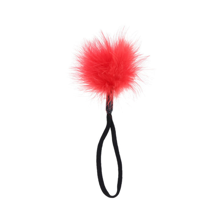 A fluffy red pom-pom on a black elastic loop, from the Ex's & Oh's Kiss Kit - 4 Piece Beginner Bondage Kit, displayed against a white background.