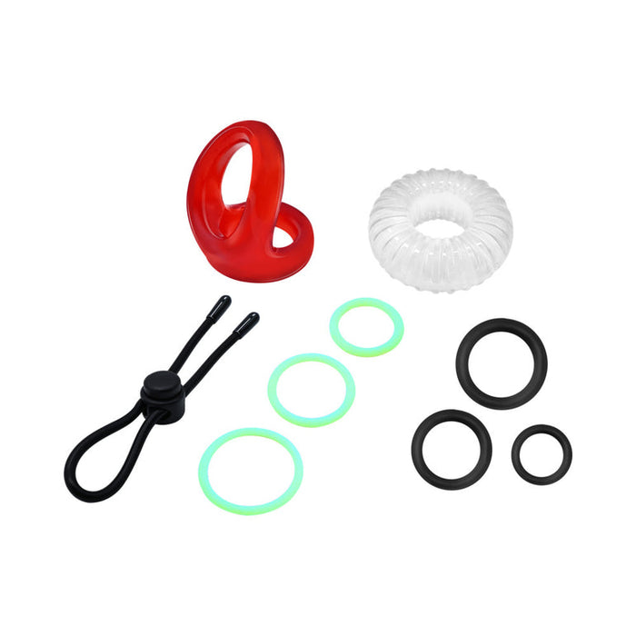 The Family Jewels Penis Ring Variety Pack features rings in assorted shapes, sizes, and colors—red, clear, black, and green—arranged on a white background to form an enhancer set for longer-lasting erections.