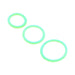 Three glow-in-the-dark rings from the Family Jewels Penis Ring Variety Pack, each in a different size, are arranged diagonally on a white background.