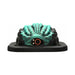 A cake modeled after the Dragon Grinder - Vibrating Silicone Fantasy Pad, with teal-green and black textured ridges, a prominent orange and black eye in front, sits on a black rectangular base.
