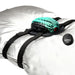 A gray pillow with black straps holds the turquoise and black Dragon Grinder - Vibrating Silicone Fantasy Pad, featuring dragon scale designs. Includes a small "Creature Couch" remote. This waterproof, rechargeable pad brings fantasy to life.