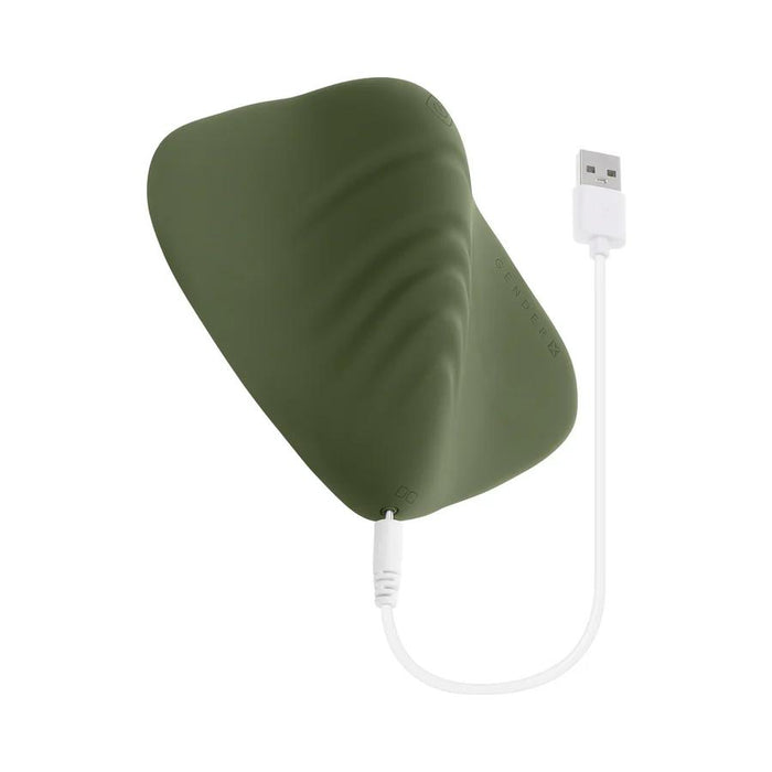 The Gender X Pleasure Pad Rechargeable Grinding Pad & Stroker is a wavy, green, leaf-shaped silicone vibrator with a textured surface, shown connected to a white USB charging cable against a white background.