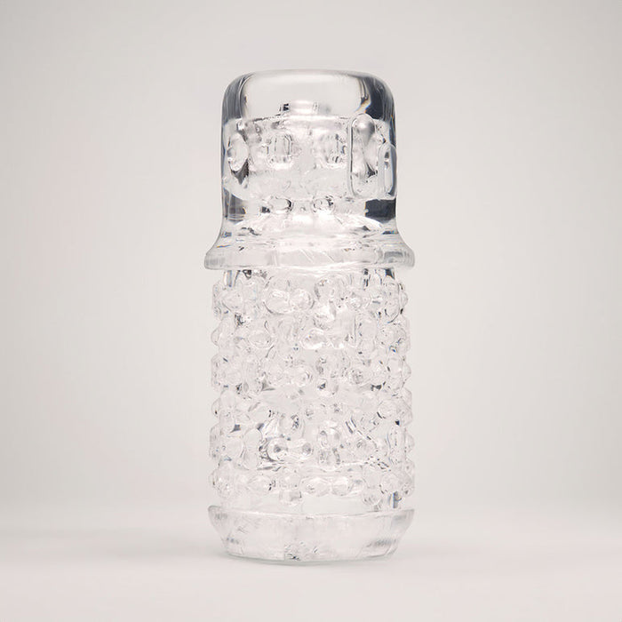 The Handy Dream Collection Chrysm Sleeve, with its clear, cylindrical shape and textured bubbled surface reminiscent of glass, stands upright against a plain light gray background, evoking a unique tactile experience.