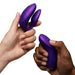 Two hands—one light-skinned, one dark-skinned—hold the We-Vibe Chorus Pro Wearable Couples' Vibrator with Triple Motors & Remote in purple against a white background. It features Fusion Wave Technology for precise G-spot stimulation and enhanced pleasure.