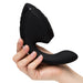 A hand holds the Womanizer Next Duo Pleasure Air + Vibration Blended Orgasm Stimulator, a black, curved silicone device with an ergonomic contoured handle and bulbous end, shown against a plain white background.