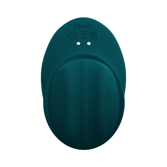 The Riana Circular Clitoral Rubbing Vibrator is a teal, oval-shaped toy made from body-safe silicone with two small holes, “blush” engraved on top, certification markings, and a smooth, curved surface for a minimalist design.