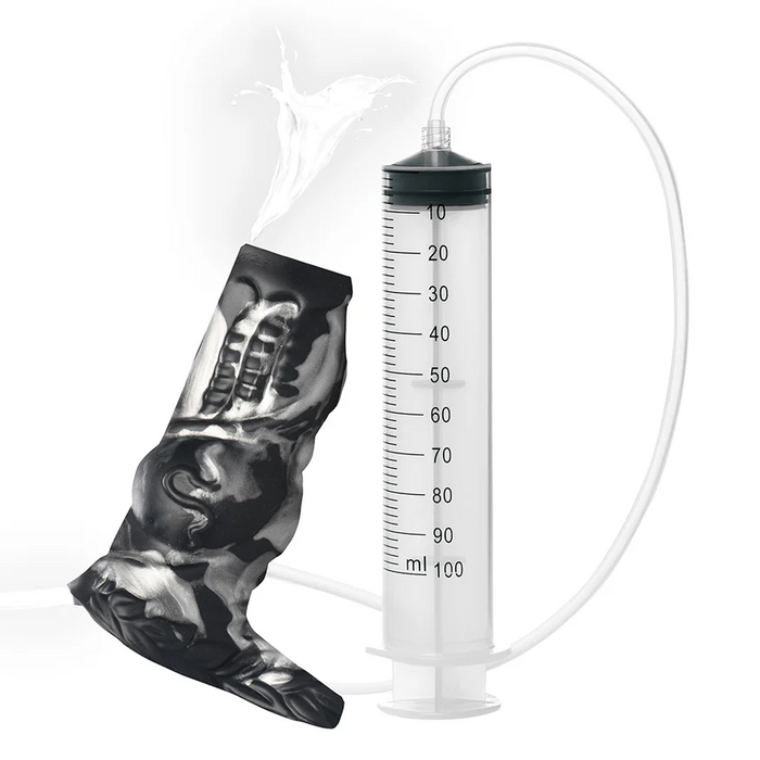 The Night Prowler Squirting Penis Enhancer is shown connected by a tube to an anatomical model, with liquid squirting out the top to demonstrate its use—displayed here as an educational accessory.