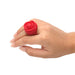 A hand with light skin and manicured nails wears the Bloomgasm Rose Ring Finger Vibrator, a large body-safe silicone rose-shaped ring, on the middle finger against a white background.