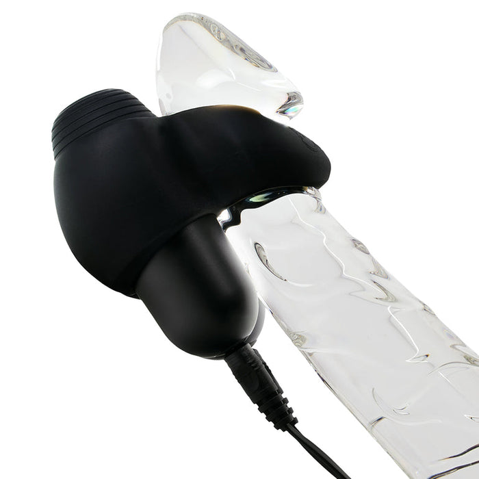 A Hot Octopuss Jett Turbo Hands-Free Masturbator in black is attached to the shaft of a clear, textured glass dildo. Its cord indicates powerful frenulum stimulation for enhanced pleasure.