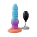 The Splash Nova Squirting 10 Inch Glow in the Dark Creature Dildo is a colorful, textured silicone toy with a blue to purple to orange gradient, attached to a black hand pump by a clear tube, and stands upright on a flat base.