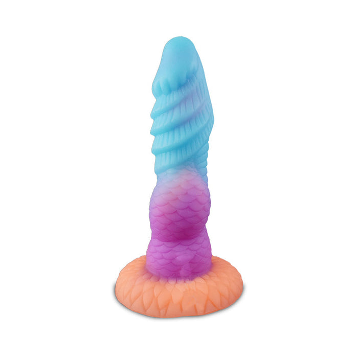 The Splash Nova Squirting 10 Inch Glow in the Dark Creature Dildo features a silicone spiral and scale texture with blue at the tip, purple in the center, and orange at the base, mimicking a mythical tentacle tail.