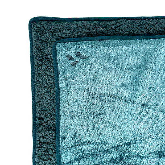 A close-up of two folded Splash Blanket The OG Waterproof Blankets in teal, crafted from plush micro-velvet with a soft, cozy texture and a small embroidered corner design. Perfect for comfort and style in a compact size.