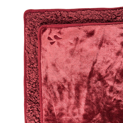 A close-up of the Splash Blanket The OG Waterproof Blanket - Medium, featuring a soft, plush deep red fabric with a textured border and a subtle paw print detail in one corner.