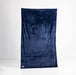 The Splash Blanket Furlush Luxurious Faux Fur Waterproof Blanket - Large in dark blue velvet hangs vertically against a plain white background, showcasing its plush, soft texture and a small white tag in the bottom left corner.