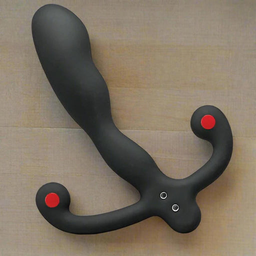 The Aneros Helix SYN V is a black, curved vibrating hands-free prostate massager with dual rounded handles featuring red tips, shown on a beige surface—ideal for intense prostate stimulation.