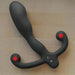The Aneros Helix SYN V is a black, curved vibrating hands-free prostate massager with dual rounded handles featuring red tips, shown on a beige surface—ideal for intense prostate stimulation.