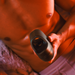 A shirtless person reclines on a bed under warm orange lighting, holding an Arcwave Ion 2 Penis Masturbator with Pleasure Air Suction—a silicone male stroker featuring innovative suction technology.