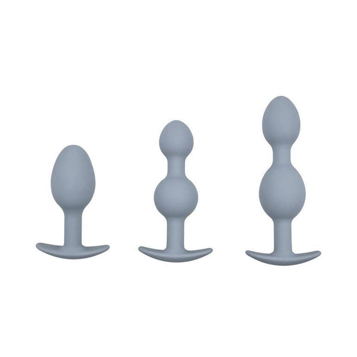The Adam & Eve Vibra Ball Weighted Butt Plug Trio & Anal Trainers includes three gray silicone plugs with flared flat bases, featuring smooth, tapered, and beaded designs in various sizes to suit different anal play preferences.