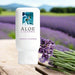 A bottle of Aloe Cadabra French Lavender Aloe Based Gentle Lubricant 2.5 oz rests on a wooden surface by fresh lavender, with a blurred lavender field and mountains behind, highlighting its organic aloe vera formula for pure relaxation and comfort.