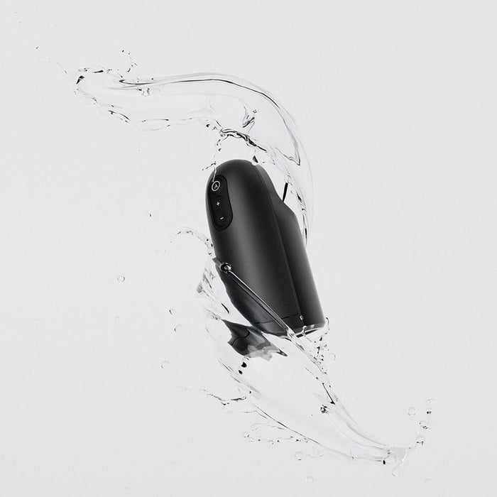 The Arcwave Ion 2 Penis Masturbator with Pleasure Air Suction floats midair, encircled by dynamic water splashes against a light background, emphasizing its sleek black design and innovative suction technology.