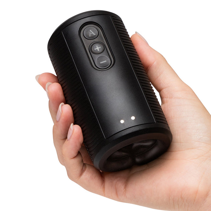 A hand holds the Arcwave Zing Adjustable Vibrating Silicone Masturbator, a black cylindrical device featuring three buttons and two small indicator lights on its surface.