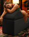 A woman in a green outfit lounging gracefully on a Liberator Aria Chaise Sex Lounger - Black, with a warm and cozy ambiance in the background.