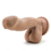 The Blush Au Naturel 6.5 Inch Dual Density Suction Cup Dildo in Mocha is shown against a plain white background. This realistic, flesh-toned silicone dildo features detailed sculpting, including a pronounced head, veins, and testicles. Designed with Dual Density Sensa Feel for a lifelike touch and equipped with a suction cup base compatible with strap-on harnesses for hands-free use.