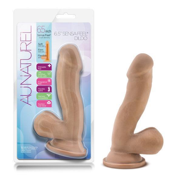 A realistic, medium-toned dual density dildo with a suction cup base is shown beside packaging labeled "Au Naturel Realistic Dual Density 6.5 Inch Medium Tone Suction Cup Dildo," featuring "soft, firm, flexible" and strap-on compatibility.