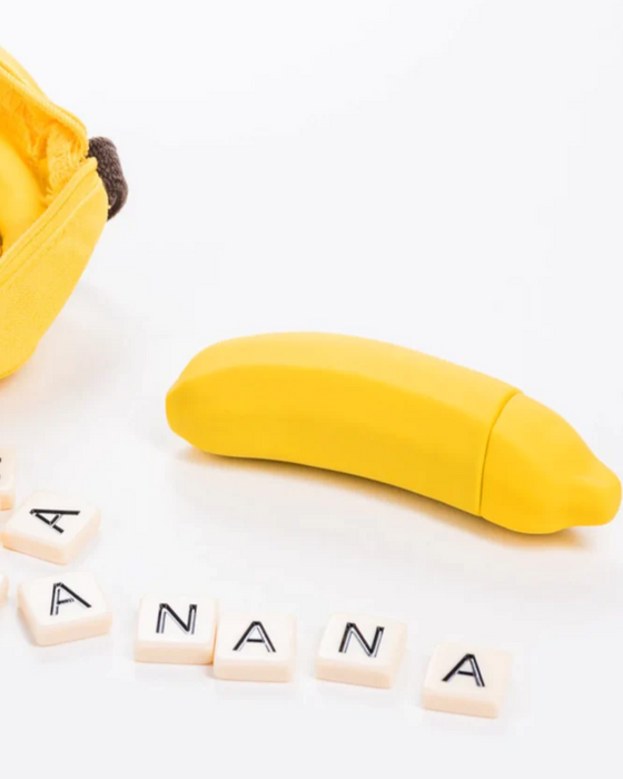 Banana Emojibator Vibrator laying on white background with banana spelled out in tiles 