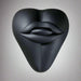 The Bananapants Kissi Dildo Base features a black, sculptural heart shape with abstract lips and tongue on its surface. Crafted from body-safe silicone, it's shown against a white background.