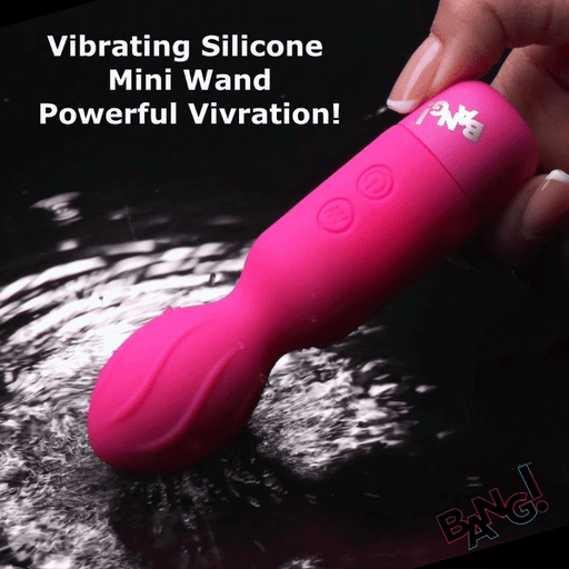 A hand holds the Bang Flexible Beginner Mini Wand Vibrator—a bright pink silicone mini wand with a textured head—above rippling water. White text reads, "Powerful Vibration!" The word "BANG!" appears in colorful letters, ideal for clitoral stimulation.