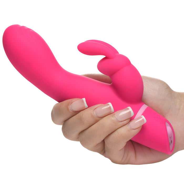 A hand holds the Bang Silicone Rabbit Vibrator with G-Spot Stroking Motion, a bright pink toy featuring dual independent motors and a smaller rabbit ear-shaped external stimulator for intense pleasure.
