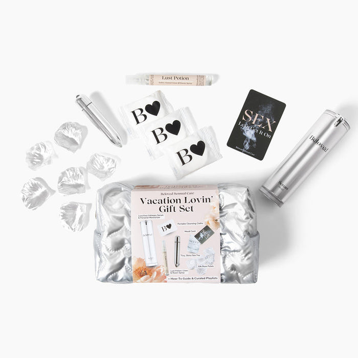 The Beloved Vacation Lovin' Intimacy Kit features a silver cosmetic bag with travel perfume spray, condoms, flower petals, a lipstick-sized item, "Love Potion" tube, and a card reading "SEX," perfect for sensual getaways.